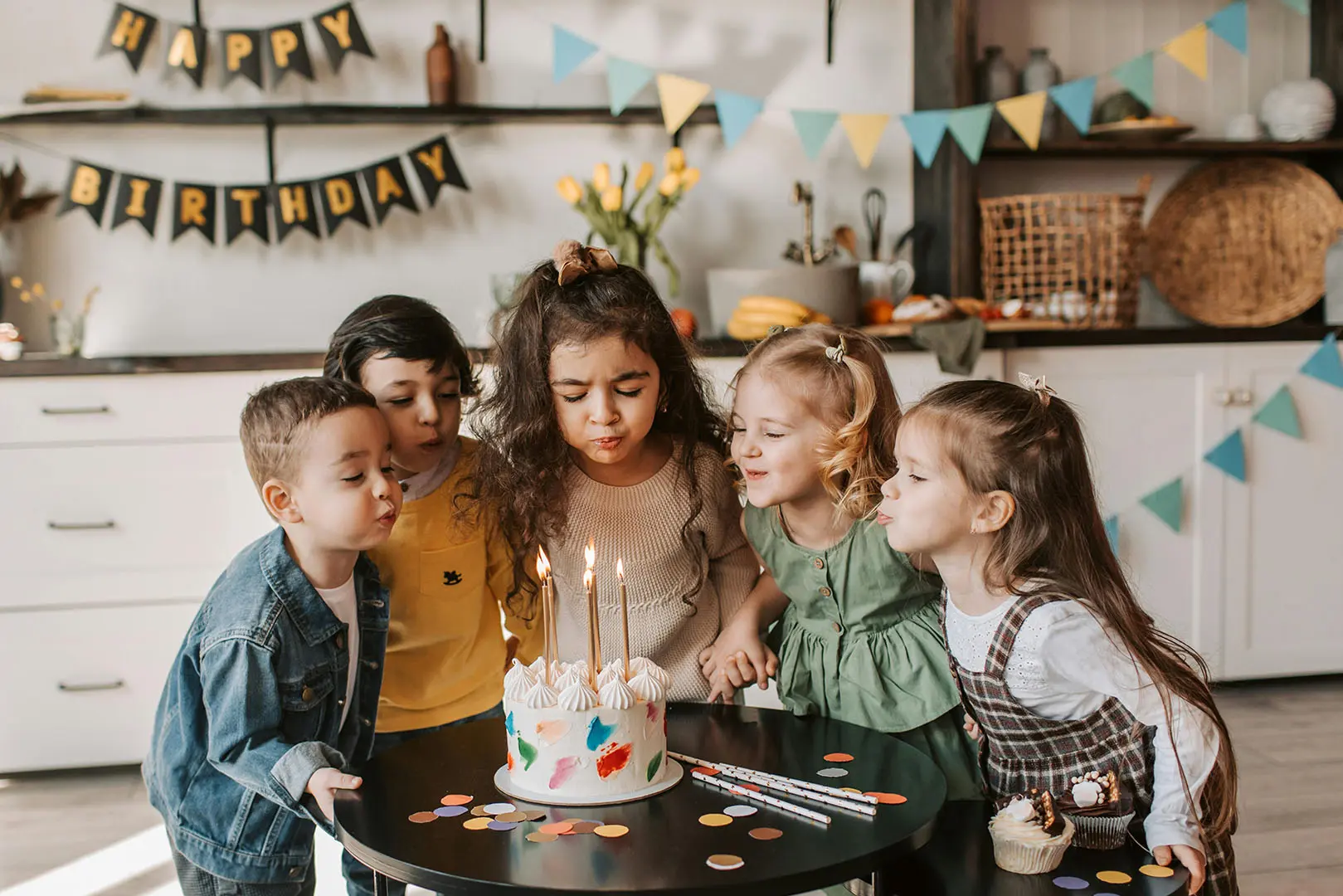 A group of children sitting around a birthday cake.