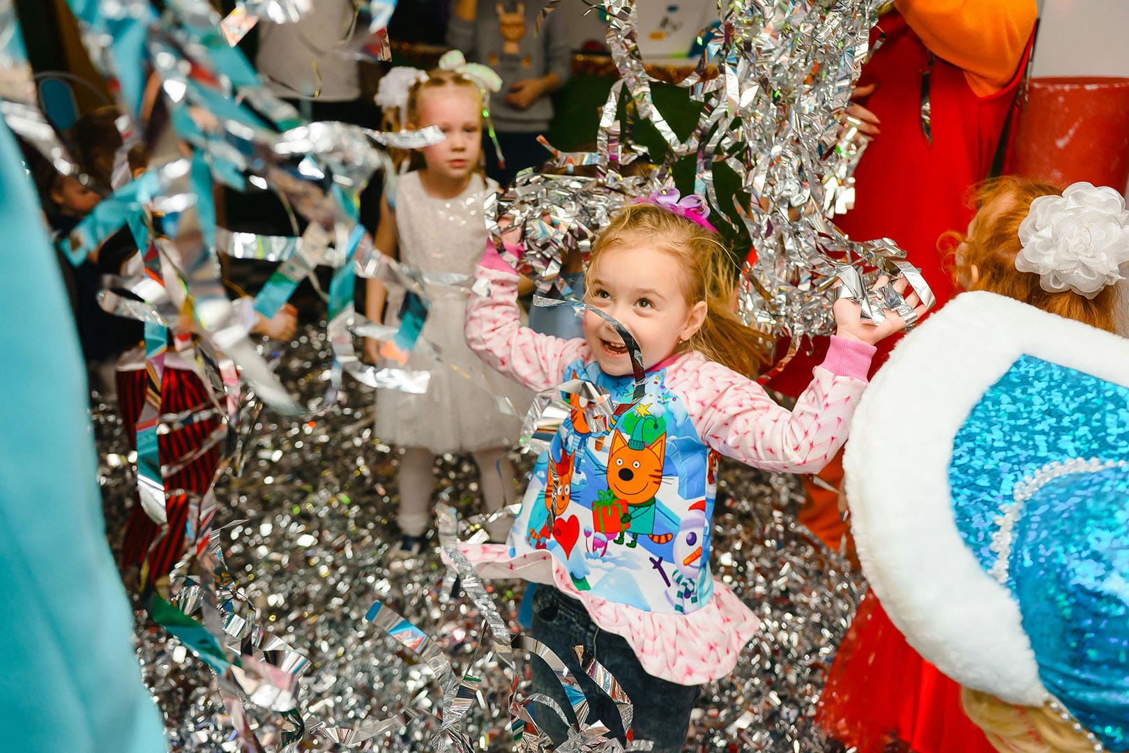 Two little girls standing in a room with silver tinsel.